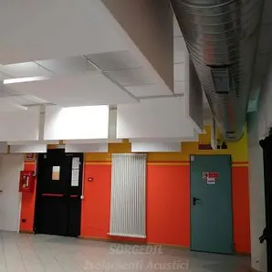 Baffles acustici su soffitto tecnico con luci e tubazioni a vista<br /><br />